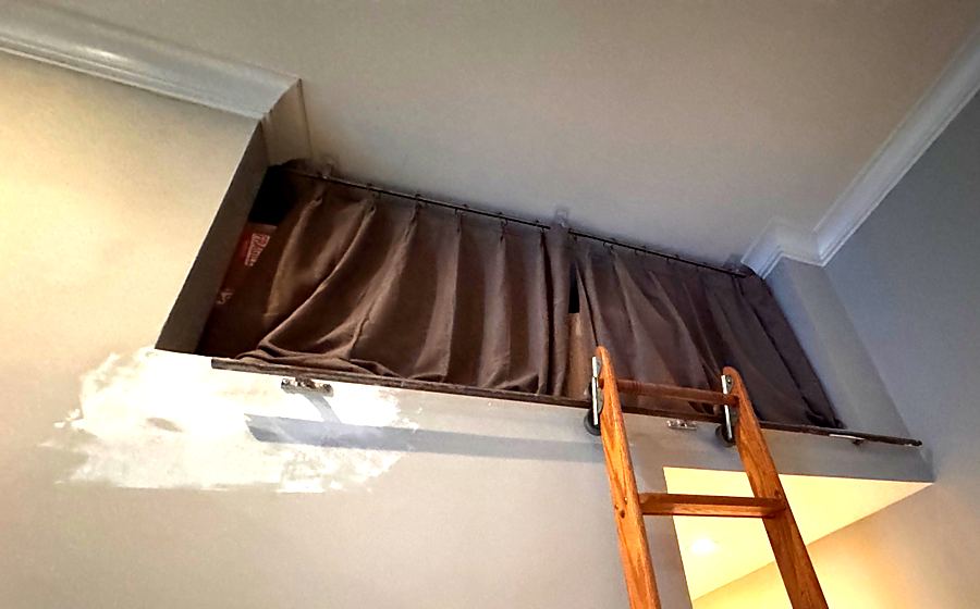 Drywall patch with joint compound on a wall below a library ladder